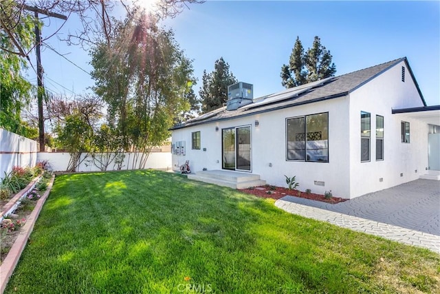 back of property featuring central AC, a lawn, and solar panels