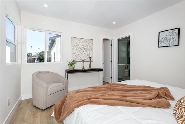 bedroom with ensuite bathroom and light wood-type flooring