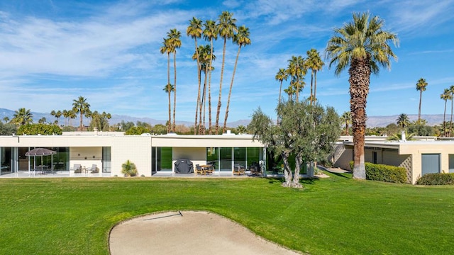 rear view of property with a mountain view, a lawn, and a patio