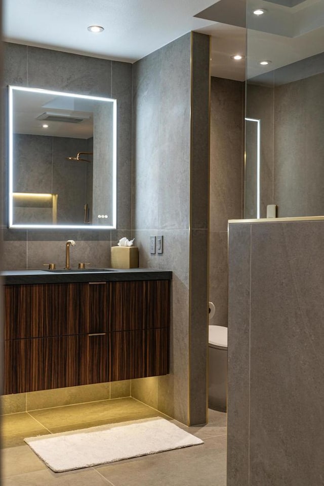 bathroom featuring toilet, a shower, tile walls, and vanity