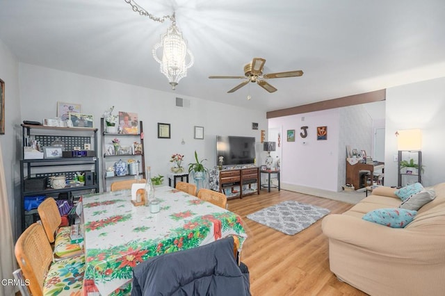 dining area featuring hardwood / wood-style flooring and ceiling fan with notable chandelier