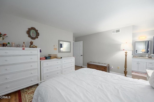 bedroom with ensuite bathroom and light hardwood / wood-style floors