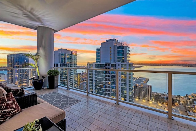 balcony at dusk featuring a water view