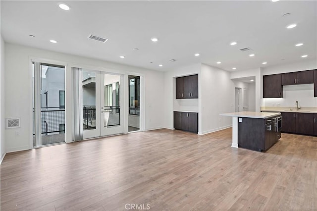 kitchen with dark brown cabinetry, a center island, and light hardwood / wood-style flooring