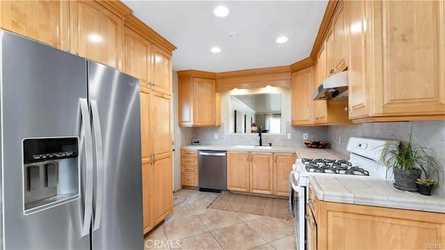 kitchen featuring appliances with stainless steel finishes, sink, light tile patterned flooring, decorative backsplash, and tile counters