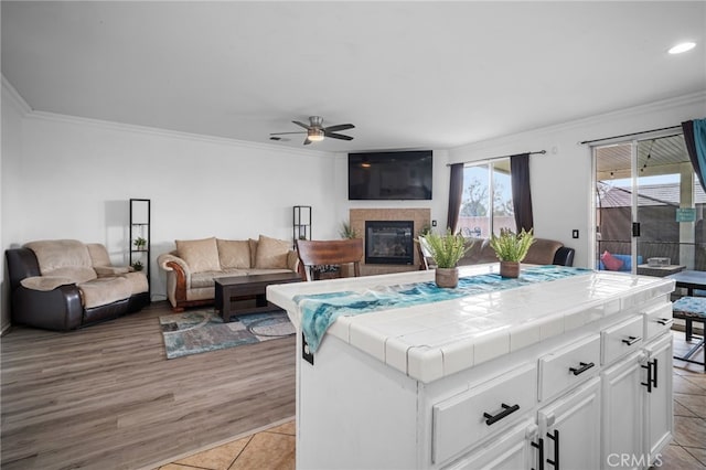 living room featuring ornamental molding, light tile patterned floors, and ceiling fan