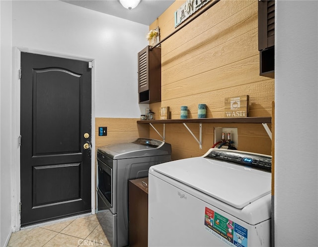 washroom featuring light tile patterned flooring, washer and clothes dryer, and wood walls