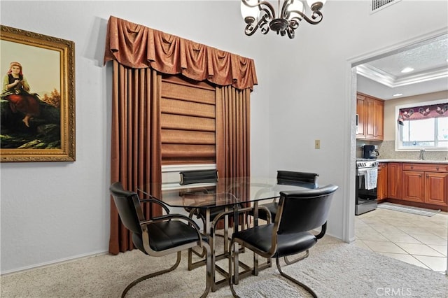 tiled dining area featuring sink, a tray ceiling, crown molding, and a notable chandelier