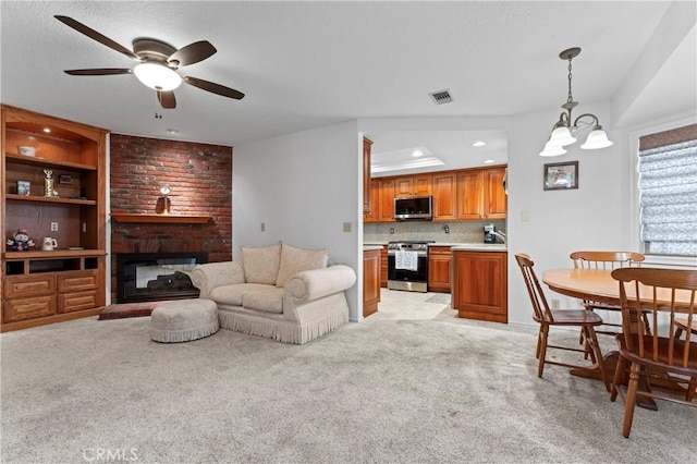 carpeted living room with ceiling fan with notable chandelier and a fireplace