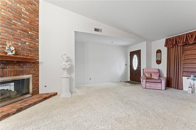 living room featuring a brick fireplace, lofted ceiling, and carpet floors