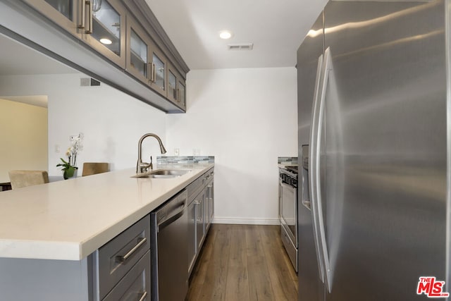 kitchen featuring sink, appliances with stainless steel finishes, dark hardwood / wood-style floors, and kitchen peninsula