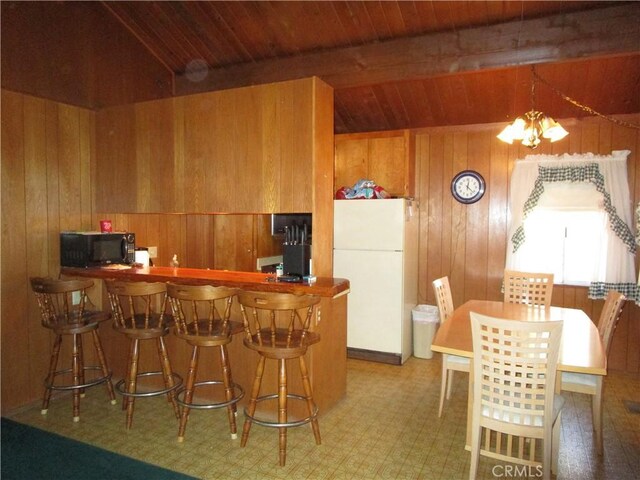 2440 Spruce Dr, Arrowbear, CA 92382 - kitchen with freestanding refrigerator, black microwave, wood walls, a wood ceiling with exposed beams, and brown cabinets