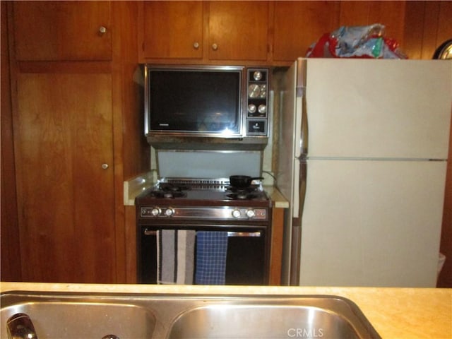 2440 Spruce Dr, Arrowbear, CA 92382 - kitchen featuring freestanding refrigerator, light countertops, brown cabinetry, and stainless steel range
