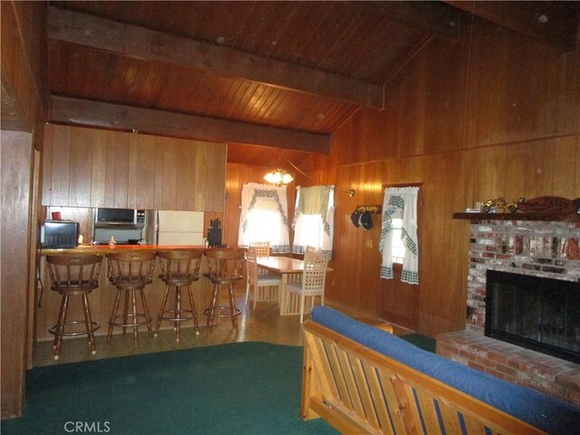 2440 Spruce Dr, Arrowbear, CA 92382 - kitchen with wooden walls, freestanding refrigerator, stainless steel microwave, a fireplace, and a wood ceiling with exposed beams