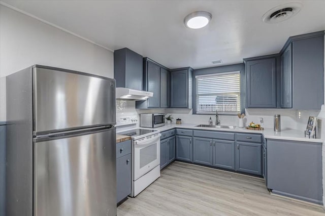 kitchen featuring sink, wall chimney range hood, light hardwood / wood-style flooring, appliances with stainless steel finishes, and tasteful backsplash