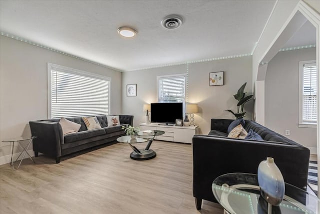 living room with ornamental molding, plenty of natural light, and light wood-type flooring