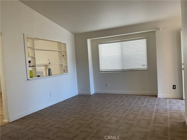 unfurnished room featuring lofted ceiling and built in features