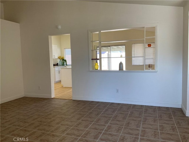 spare room featuring lofted ceiling and tile patterned flooring