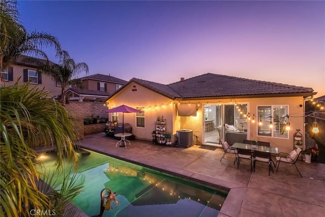 back house at dusk with a patio and central AC