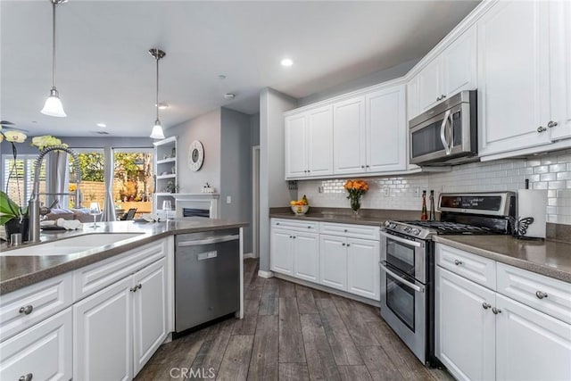 kitchen with stainless steel appliances, white cabinets, and decorative light fixtures