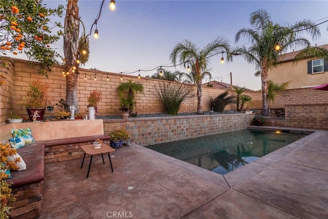 pool at dusk featuring a patio