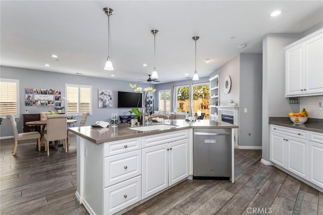 kitchen with stainless steel dishwasher, an island with sink, hanging light fixtures, and white cabinets