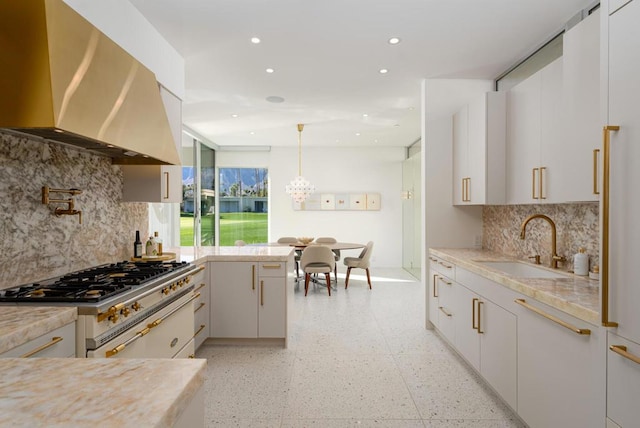 kitchen featuring sink, exhaust hood, hanging light fixtures, high end white range oven, and white cabinets