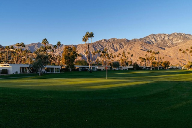 surrounding community with a mountain view and a lawn