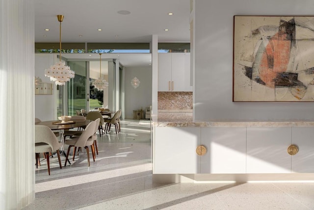 interior space with white cabinetry, hanging light fixtures, tasteful backsplash, and expansive windows