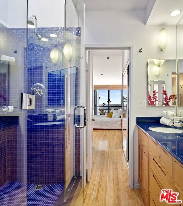 bathroom featuring vanity, a shower with shower door, and wood-type flooring