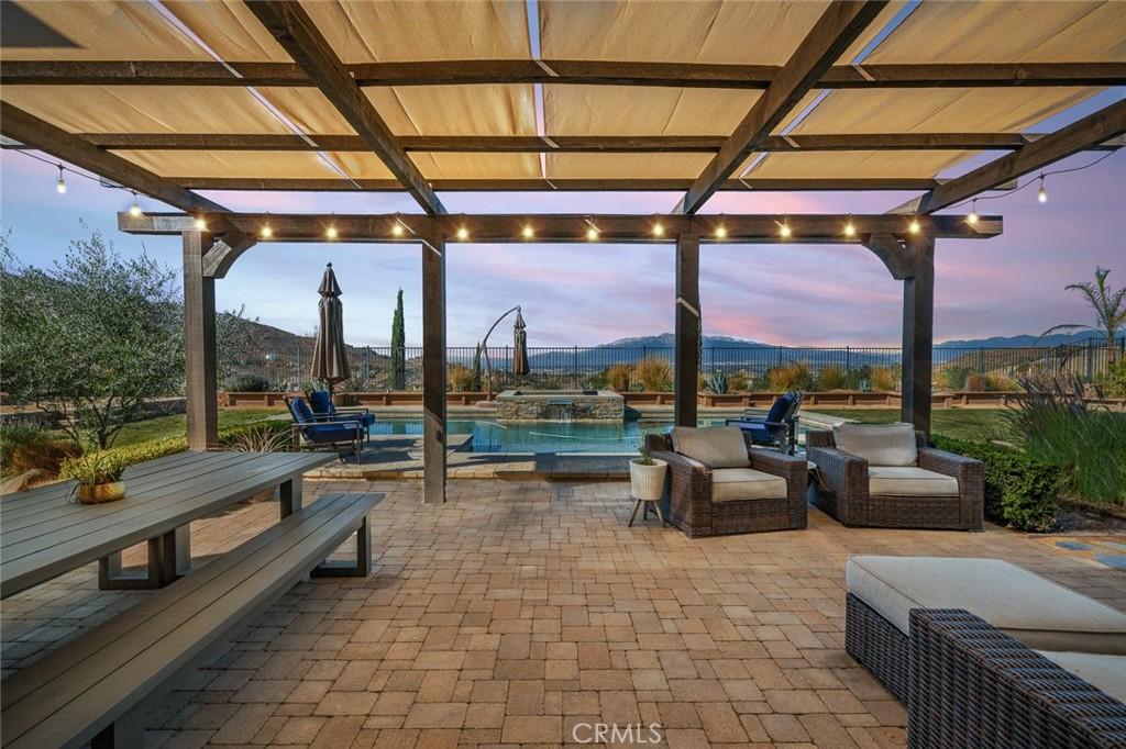 patio terrace at dusk featuring an outdoor living space, a mountain view, and a pergola