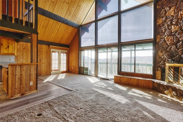 unfurnished living room featuring french doors, high vaulted ceiling, beamed ceiling, and plenty of natural light