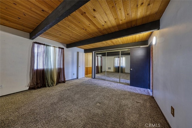 unfurnished bedroom with a closet, carpet floors, beam ceiling, and wooden ceiling