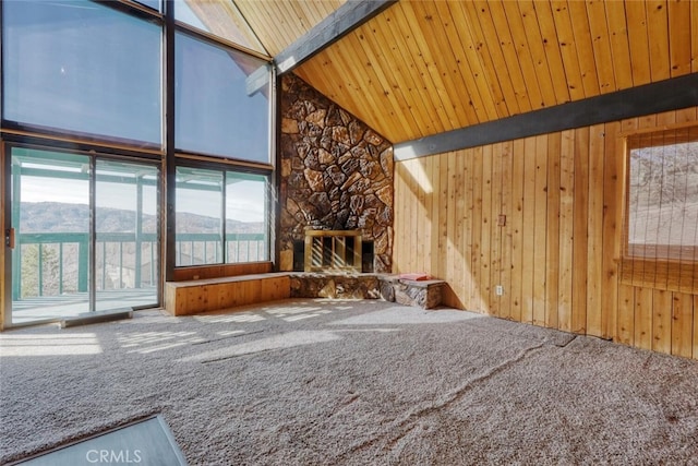 unfurnished living room featuring beamed ceiling, a stone fireplace, wooden ceiling, a mountain view, and high vaulted ceiling