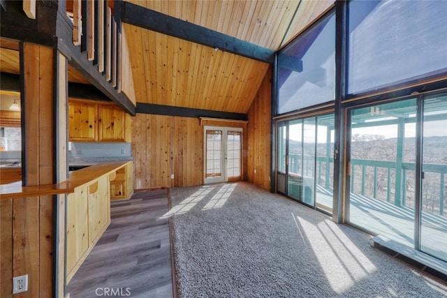 unfurnished living room with beamed ceiling, wood ceiling, french doors, high vaulted ceiling, and wood walls