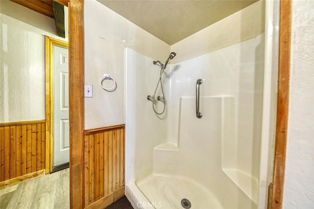 bathroom featuring wooden walls and walk in shower