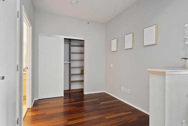 unfurnished bedroom with dark hardwood / wood-style flooring and a closet