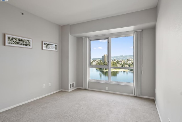 carpeted spare room with a water view