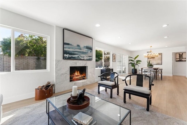 living room with a high end fireplace, plenty of natural light, and light wood-type flooring