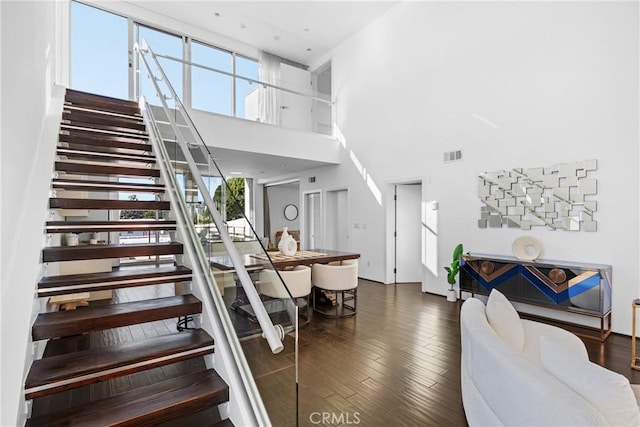 stairs with hardwood / wood-style floors and a high ceiling