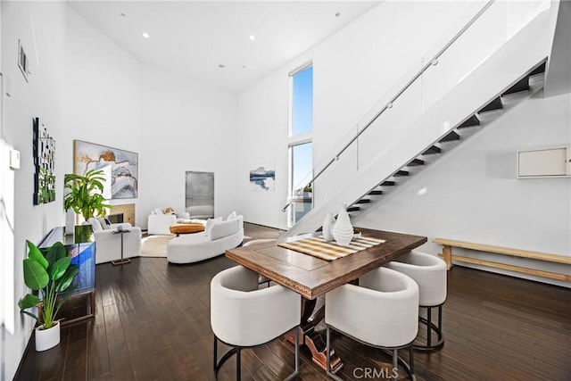 dining room with a towering ceiling and dark hardwood / wood-style flooring