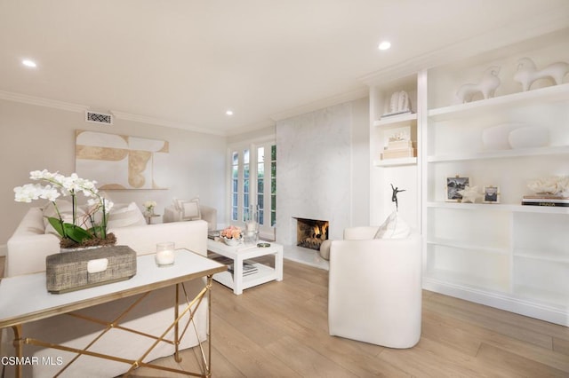 interior space featuring crown molding, a fireplace, and light hardwood / wood-style floors