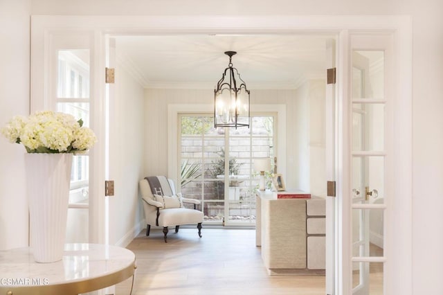 interior space featuring ornamental molding, light wood-type flooring, and a notable chandelier