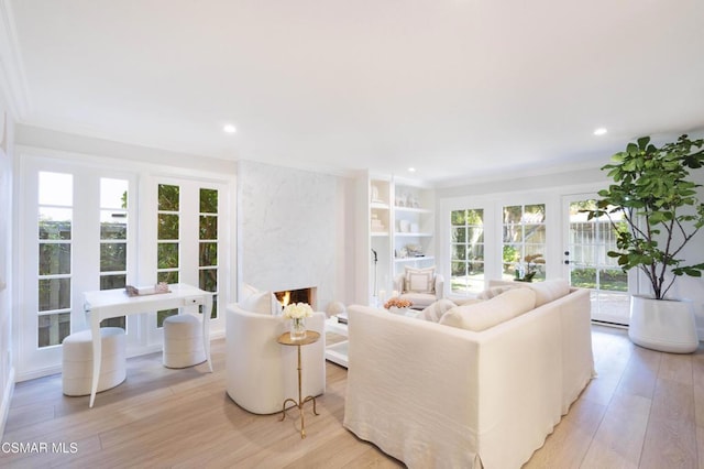 living room featuring crown molding, light wood-type flooring, and built in shelves