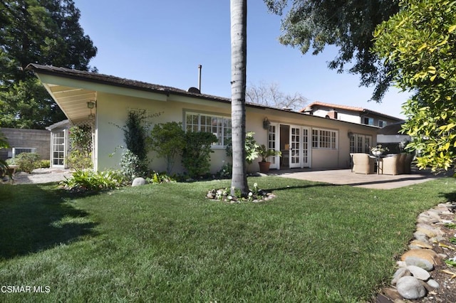 back of property with a patio, a lawn, and french doors