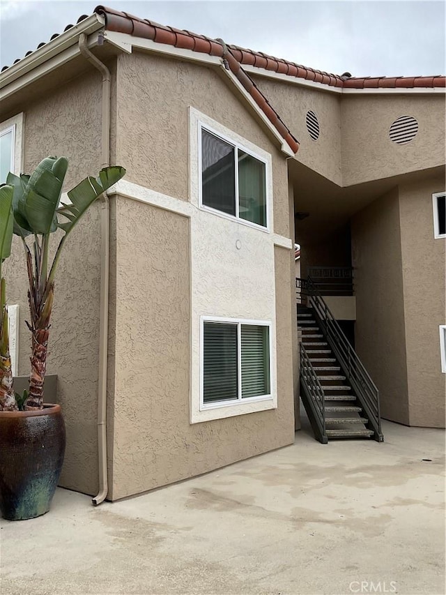 7405 Charmant Dr Unit 2320, San Diego, CA 92122 - view of home's exterior featuring a patio area, stairway, and stucco siding