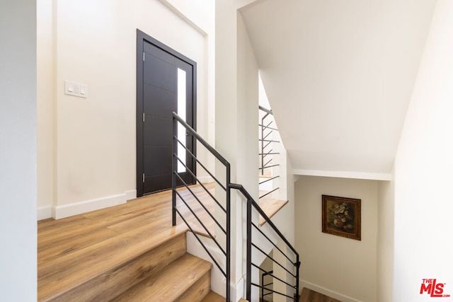 stairway featuring vaulted ceiling and hardwood / wood-style floors