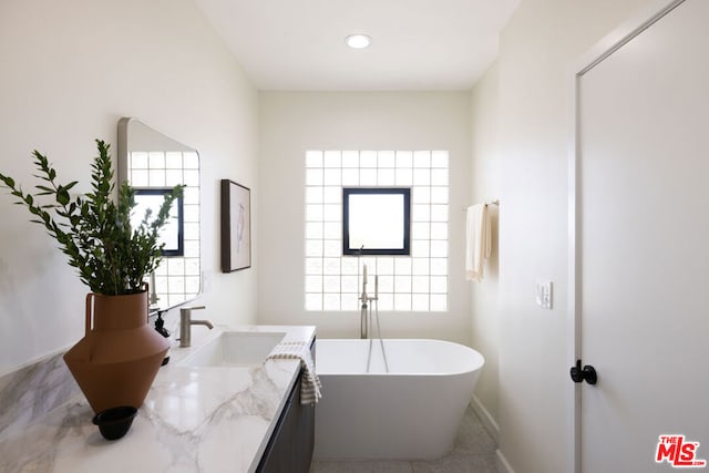 bathroom with a washtub, vanity, and tile patterned floors