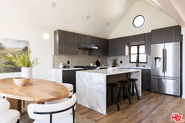 kitchen featuring hardwood / wood-style flooring, high end fridge, high vaulted ceiling, and dark brown cabinets