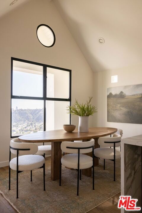 dining space featuring wood-type flooring, high vaulted ceiling, and breakfast area